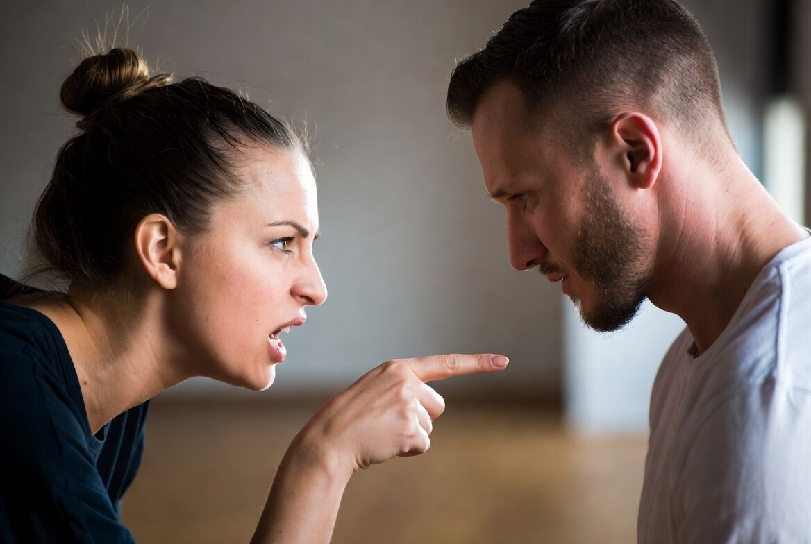 Wanita dengan marah menunjuk dan meneriaki seorang pria yang terlihat sedih saat bertengkar di dalam ruangan.