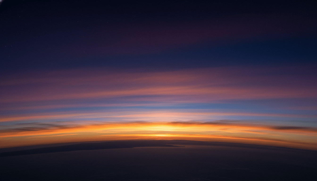 Langit matahari terbenam berwarna-warni dengan awan berlapis di atas cakrawala gelap dilihat dari ketinggian atau luar angkasa