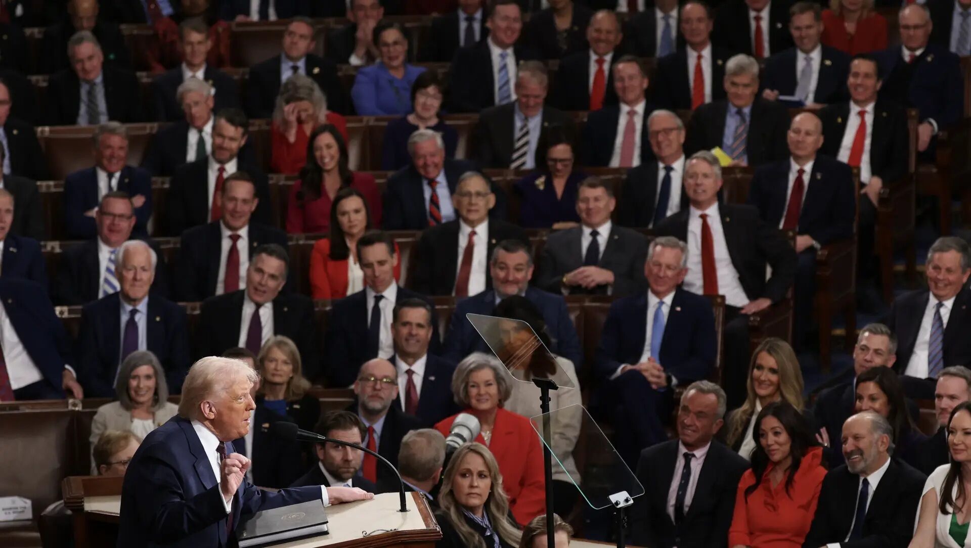 Donald Trump berbicara di podium dengan teleprompter di depan audiensi dalam suasana formal
