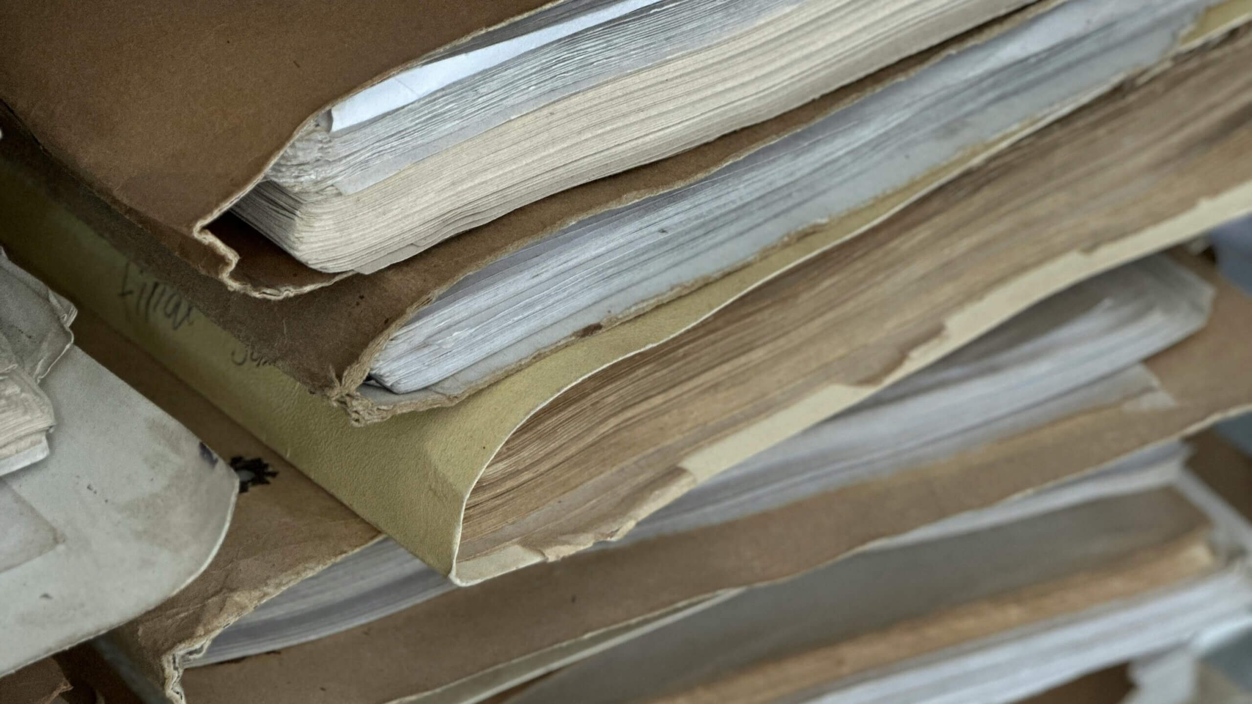 Tumpukan dokumen dan folder kertas tua dan usang dengan tepi berjumbai dan perubahan warna