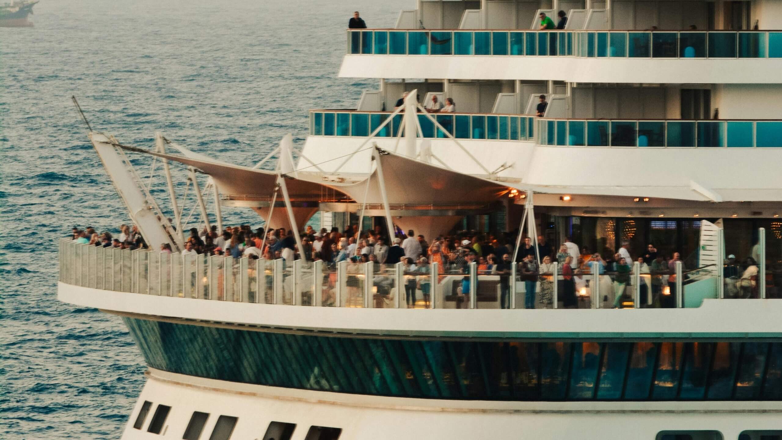 Kerumunan orang berkumpul di dek kapal pesiar dekat laut saat matahari terbenam