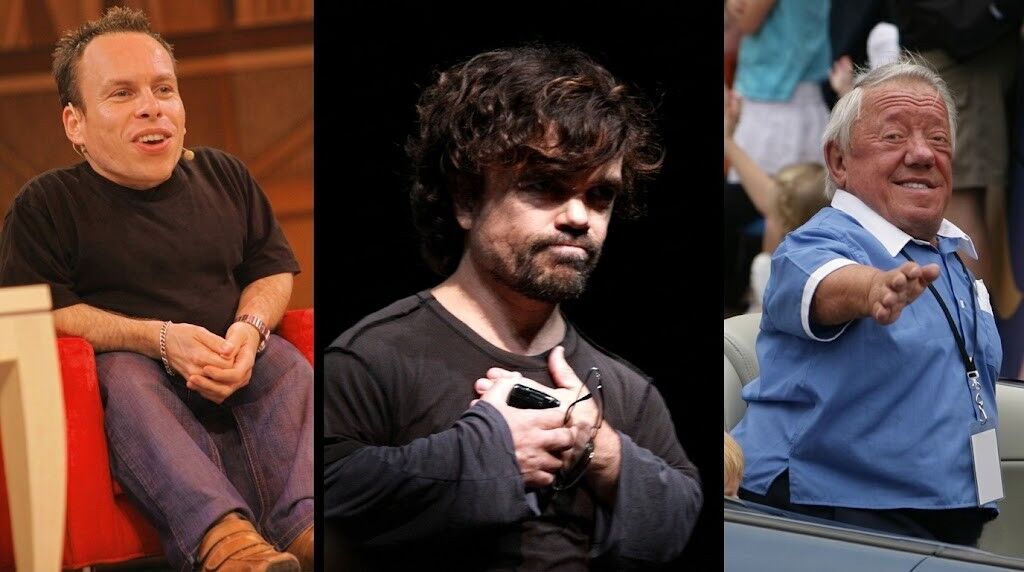 Warwick Davis duduk di kursi merah, Peter Dinklage memegang kacamata di dadanya, dan Verne Troyer melambai dengan kemeja biru.