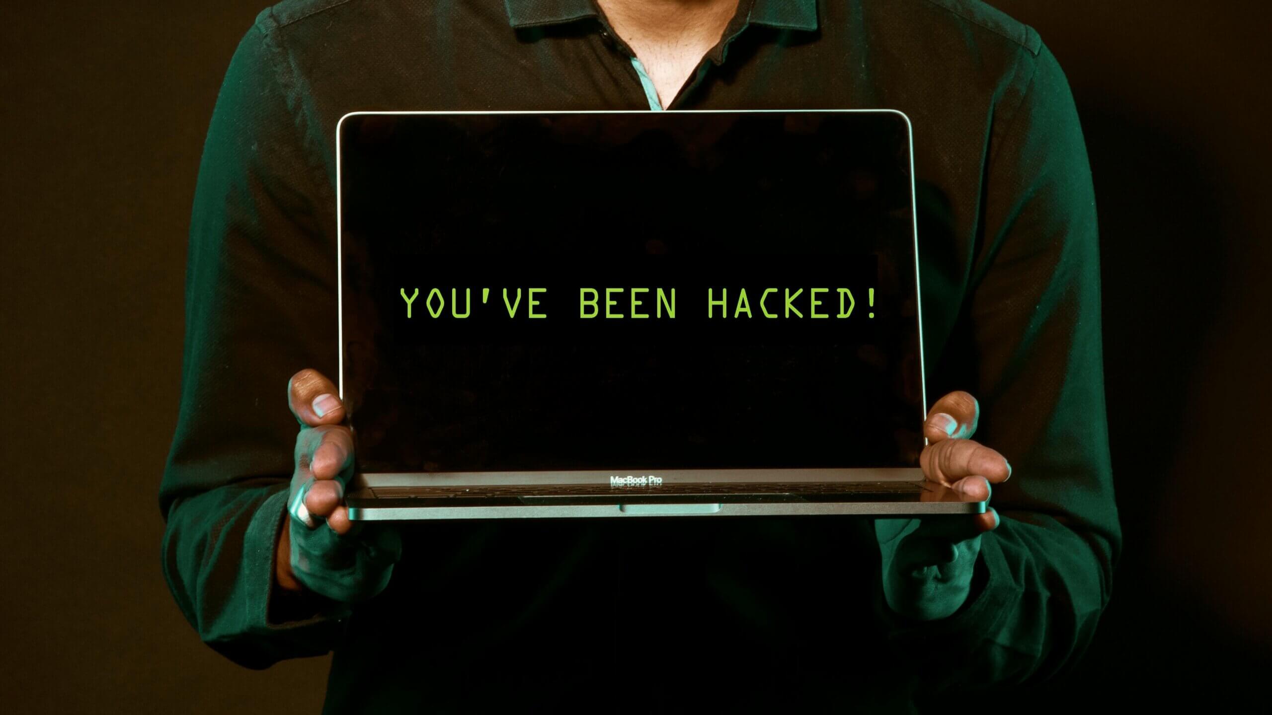 Orang yang memegang MacBook Pro menampilkan pesan 