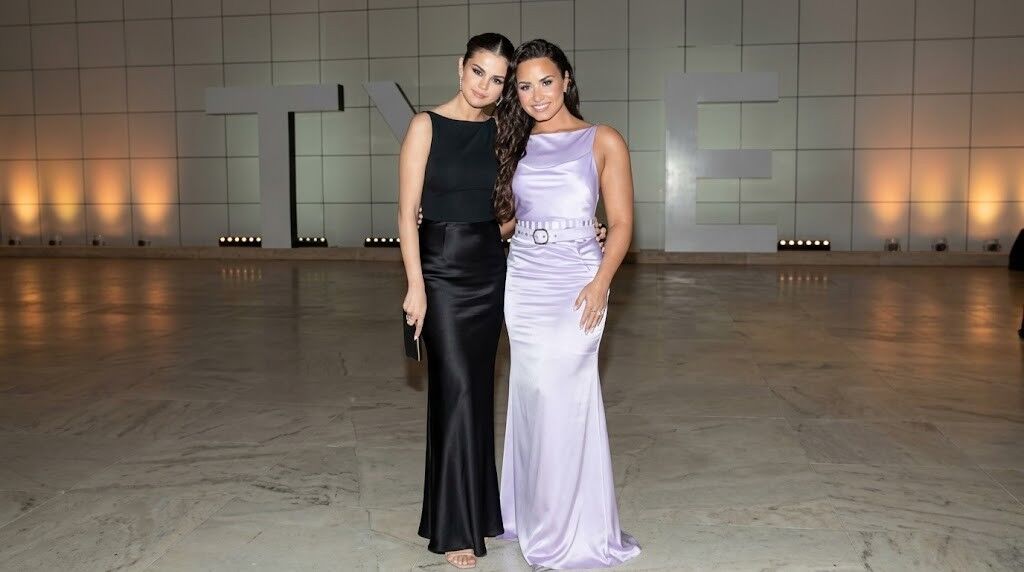 Selena Gomez dan Demi Lovato berpose bersama dalam balutan gaun malam elegan di acara formal.
