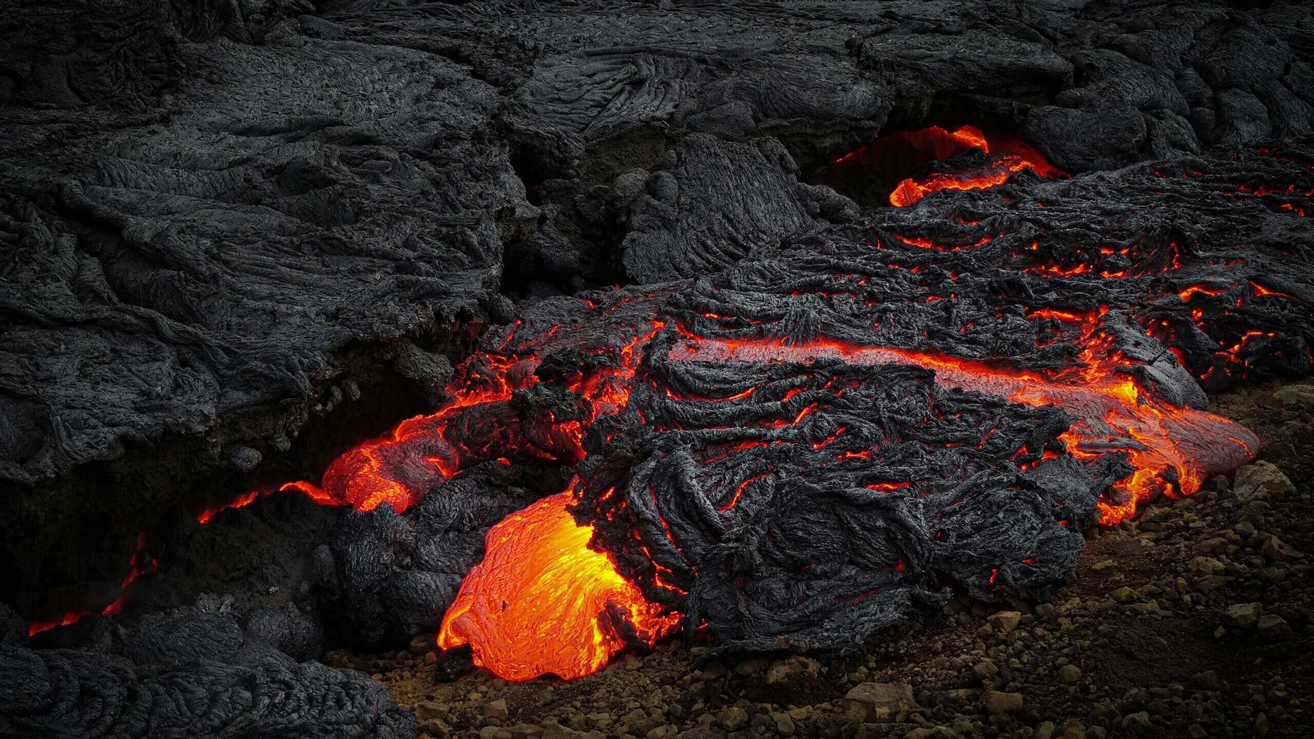 Lava cair mengalir dan mendingin menjadi batuan vulkanik hitam di permukaan berbatu