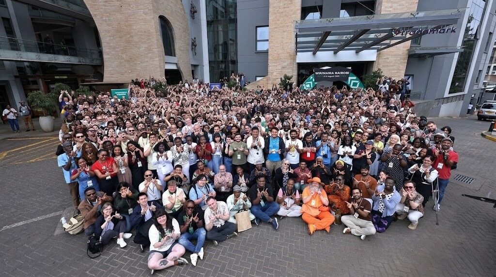 Sekelompok besar orang yang beragam berpose di luar gedung dengan a 