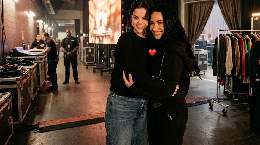 Selena Gomez dan Demi Lovato berpelukan di belakang panggung dengan pakaian kasual.