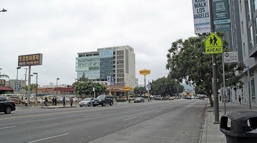 Pemandangan jalan Koreatown, Los Angeles, menampilkan restoran Denny dan tanda penyeberangan pejalan kaki.