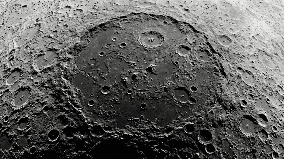 Tampilan detail permukaan Bulan yang memiliki banyak kawah dengan kawah tubrukan besar di tengahnya.