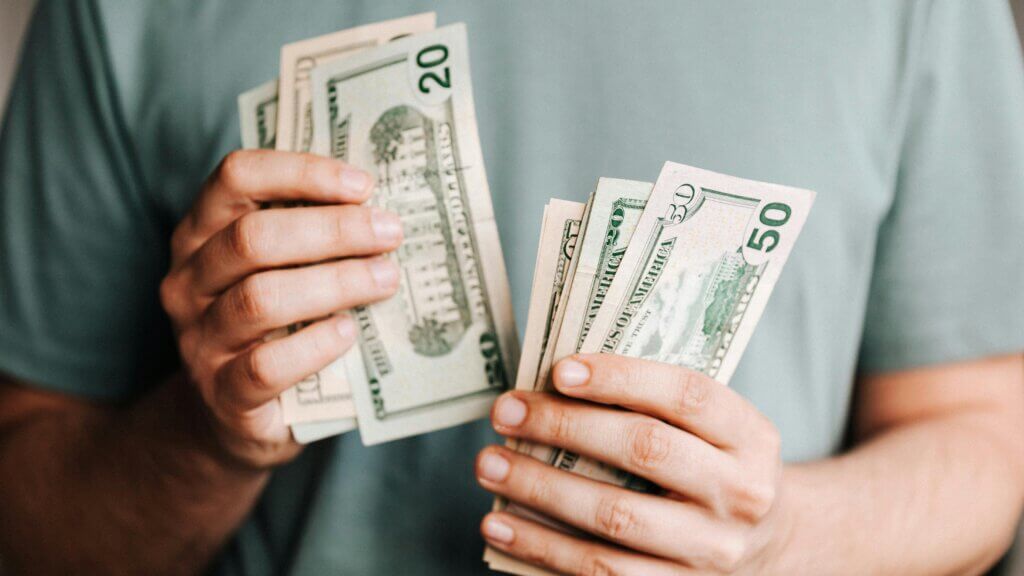Orang yang memegang dan menghitung uang dolar AS termasuk pecahan $20 dan $50