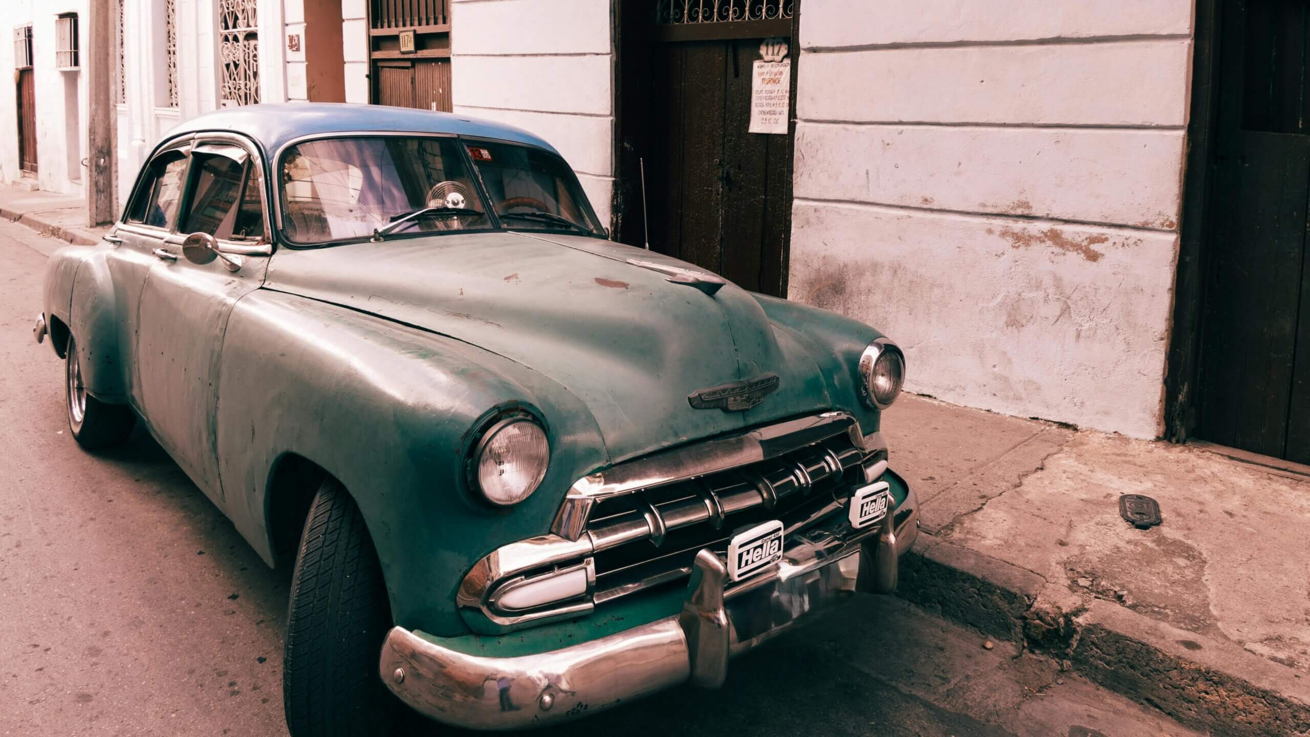 Mobil Chevrolet hijau antik diparkir di jalan dengan lampu kabut Hella dan eksterior yang lapuk