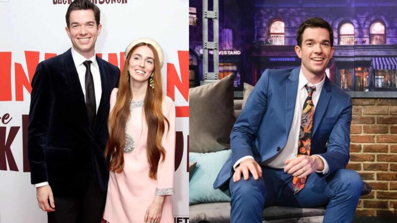 John Mulaney posing with a woman in a pink dress and sitting on a talk show set in a blue suit with a floral tie