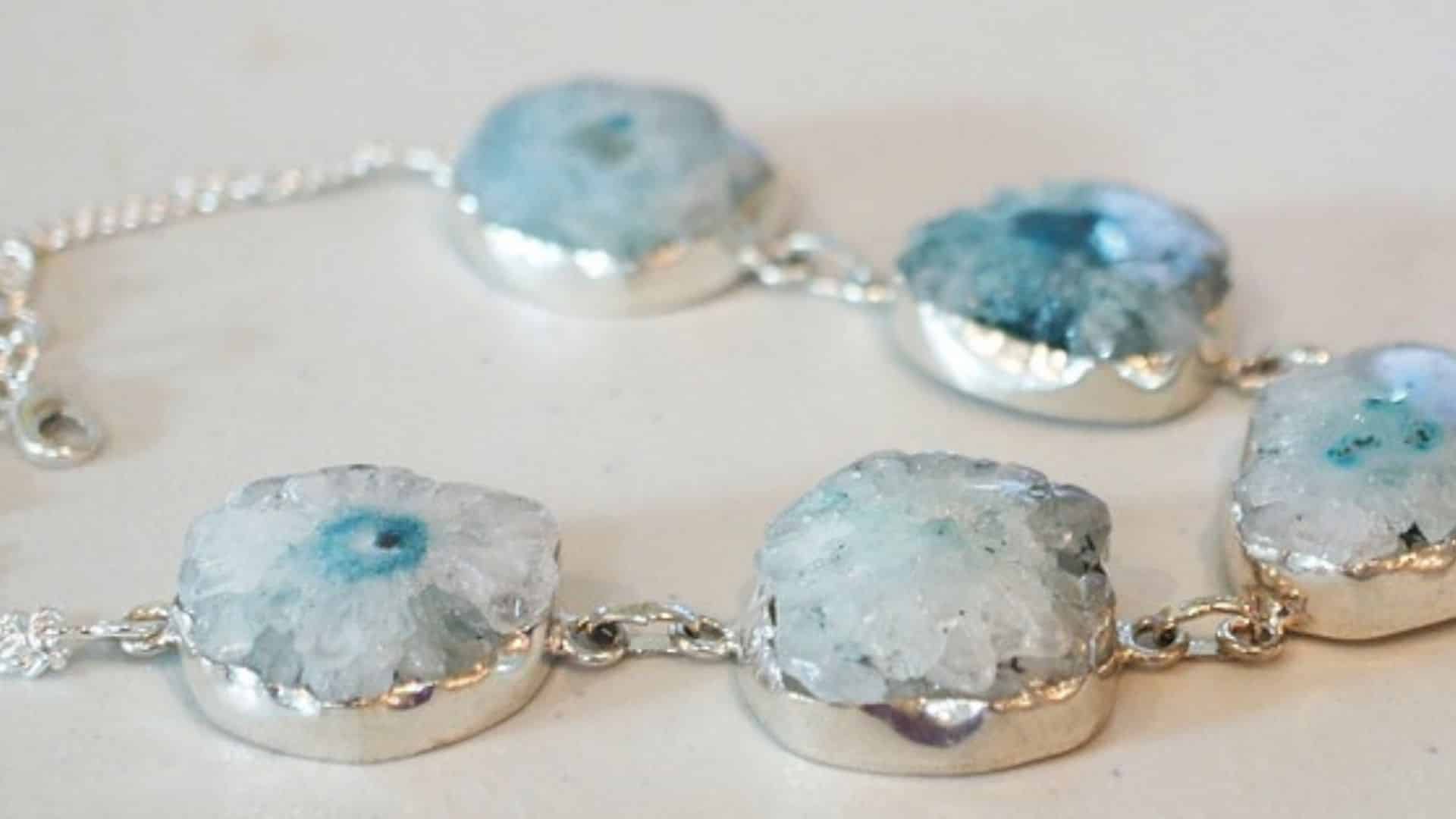 Silver bracelet with blue and white geode stone links on a white surface