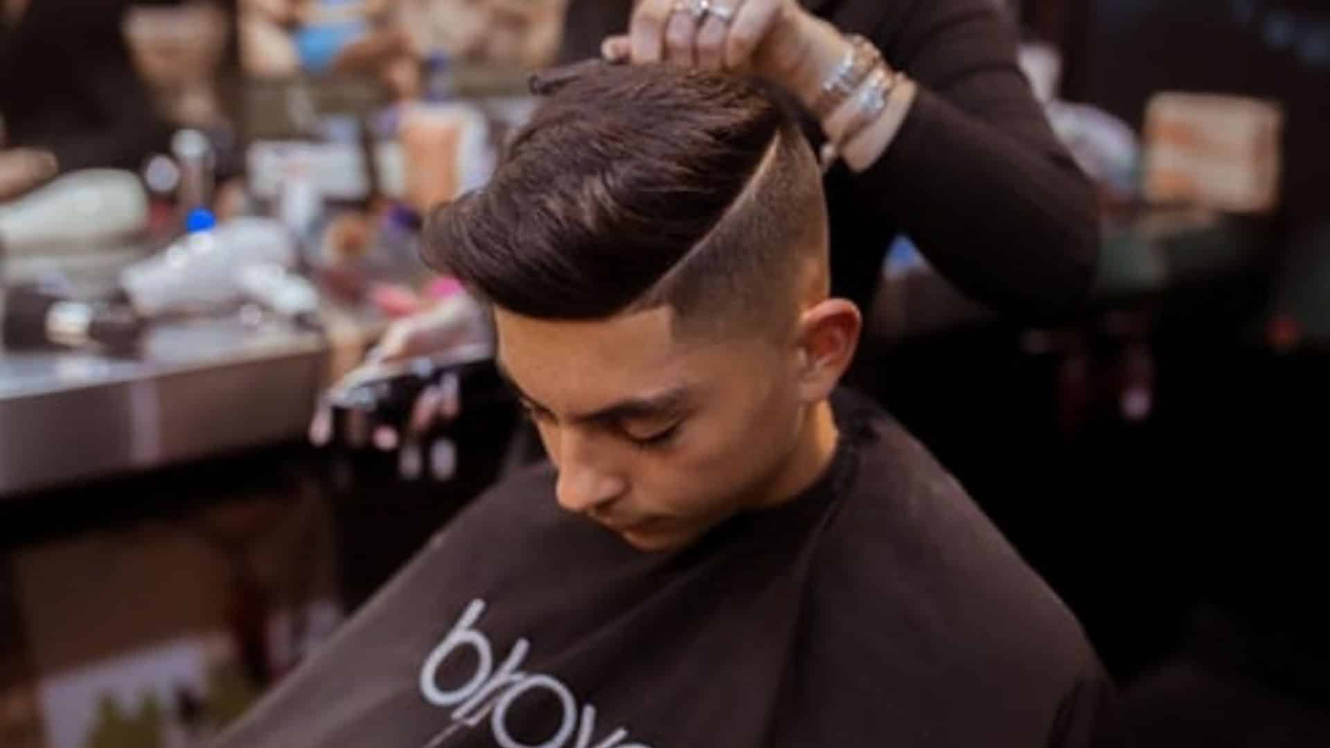 Young man getting a modern haircut with a hard part line at a barbershop