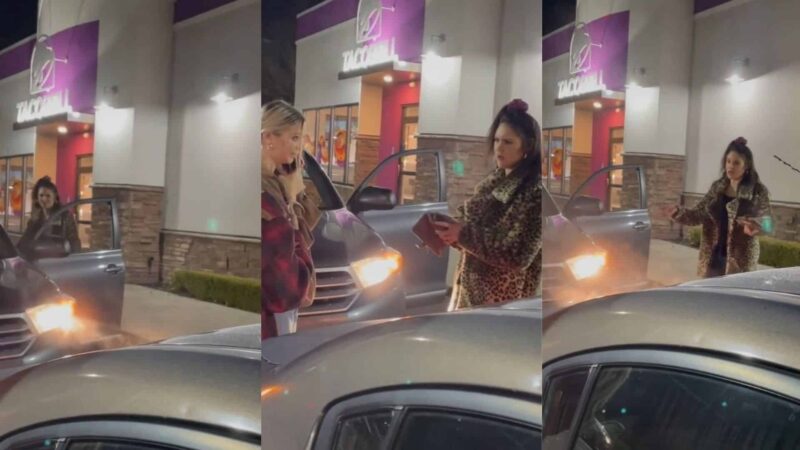 Two women talking outside a Taco Bell at night, one wearing a leopard print coat and the other holding a phone.