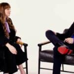 Dakota Johnson and Andrew Garfield seated and engaged in conversation during an interview.
