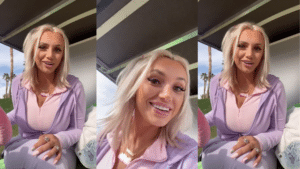 Young woman with blonde hair wearing a lavender jacket and pink top, smiling outdoors with palm trees in the background