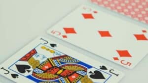 Jack of spades and five of diamonds playing cards on a white surface