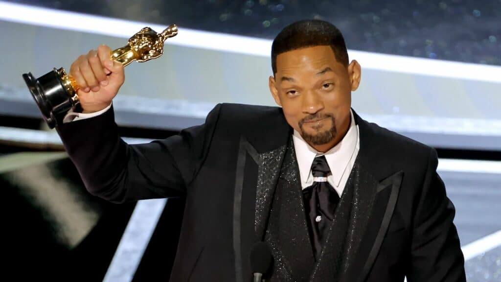 Will Smith holding an Oscar statuette while wearing a black tuxedo at an awards ceremony