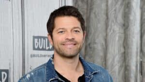 Misha Collins smiling in a denim jacket at a BUILD Series event.