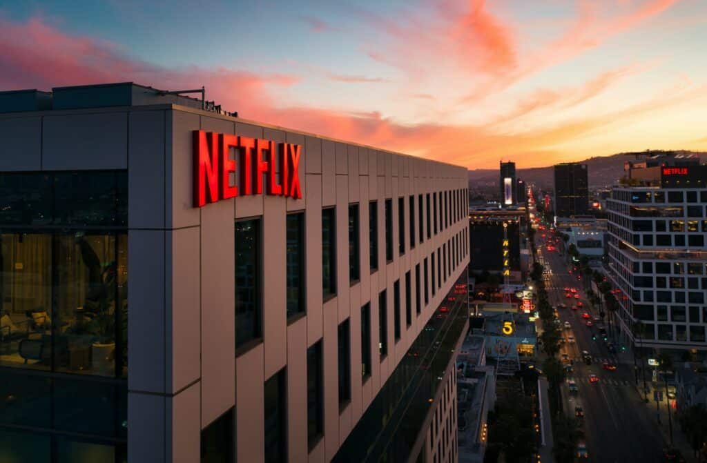 Netflix headquarters building with illuminated red logo at sunset in a cityscape.