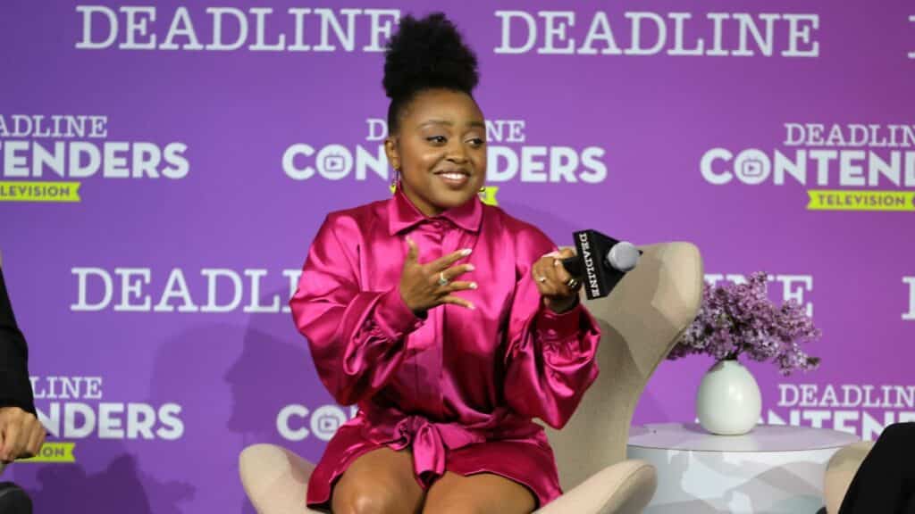 Woman in a bright pink satin dress speaking into a Deadline microphone at Deadline Contenders Television event