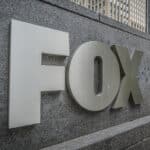 Metallic FOX logo mounted on a gray stone wall outside an office building