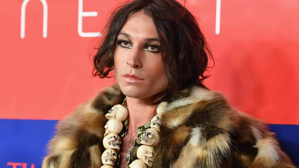 Ezra Miller wearing a fur coat and skull necklace at a Netflix event.
