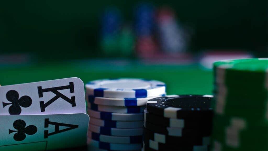Ace and King of clubs with stacks of poker chips on a green felt table