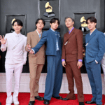 BTS members posing on the red carpet at the Grammy Awards in colorful tailored suits.