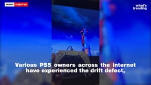Hand holding a PS5 controller in front of a screen showing a video game with text about PS5 drift defect.