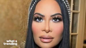 Close-up of a woman with long black hair, dramatic eyelashes, and a jeweled headband against a blurred background.