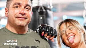 Man in green shirt and woman with blonde hair wearing black MMA gloves posing playfully in gym setting
