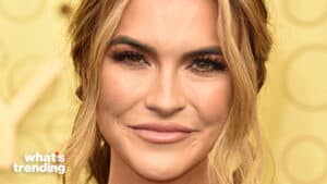 close-up of a smiling woman with blonde hair and brown eyes against a yellow background