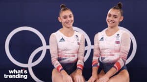 Two female British gymnasts in Team GB Olympic leotards smiling in front of Olympic rings backdrop