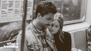 Couple sitting closely together on a subway train, woman resting her head on man's shoulder.
