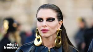 Woman with bold black eye makeup and large gold earrings wearing a black leather jacket