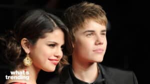 Selena Gomez and Justin Bieber posing together at a formal event with a black background.