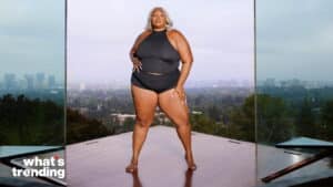 Plus-size model wearing black crop top and shorts posing in front of a cityscape with "what's trending" logo