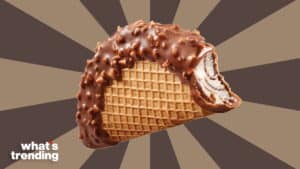 Chocolate-coated ice cream taco with waffle cone shell and nuts on a brown striped background