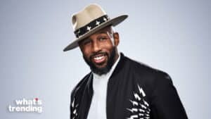 Smiling man wearing a beige hat with star band and black jacket with white lightning bolt design