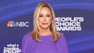 Blonde woman in purple dress posing at NBC People's Choice Awards backdrop