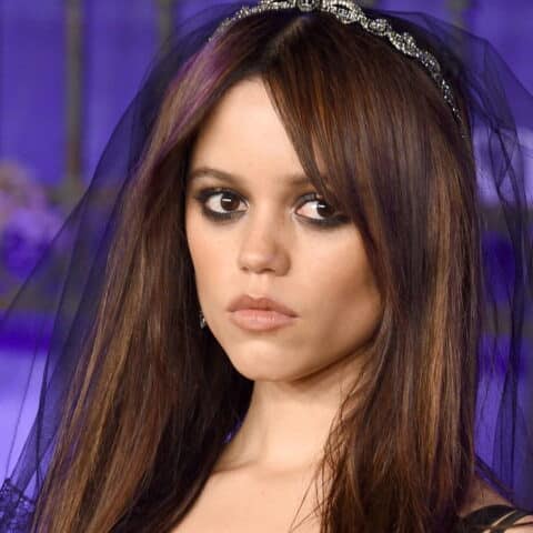 Maya Hawke wearing a black veil and smoky eye makeup at a purple-lit event backdrop