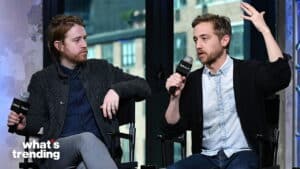Two men holding Build microphones, one speaking with raised hand during an interview or discussion.