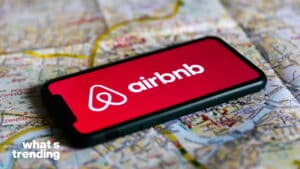 Smartphone displaying Airbnb logo on a map background with "what's trending" text in the corner