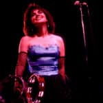 Siouxsie Sioux performing on stage with tambourines and a microphone stand nearby