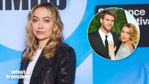 Olivia Wilde posing in front of a blue backdrop with an inset photo of Liam Hemsworth and Miley Cyrus at an event.
