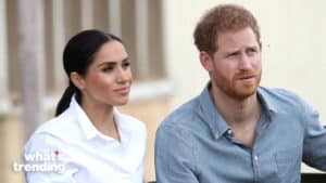 Prince Harry and Meghan Markle sitting side by side, Meghan in a white shirt and Harry in a denim shirt