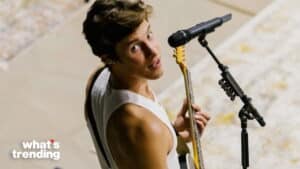 Shawn Mendes playing guitar and singing into a microphone on stage