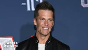 Tom Brady smiling in a black leather jacket and white shirt against a blue backdrop with "what's trending" text.